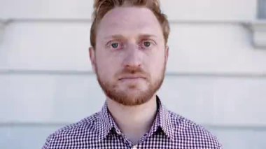 Portrait of serious ginger young adult man looking at camera outdoors