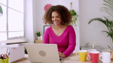 Yaratıcı iş kadını Afrikalı kadın sahibi atölyesinde dizüstü bilgisayarında bir video görüşmesi yapıyor. Ev ofisinden online çalışan mutlu online girişimci kadın. Yüksek kalite 4k görüntü