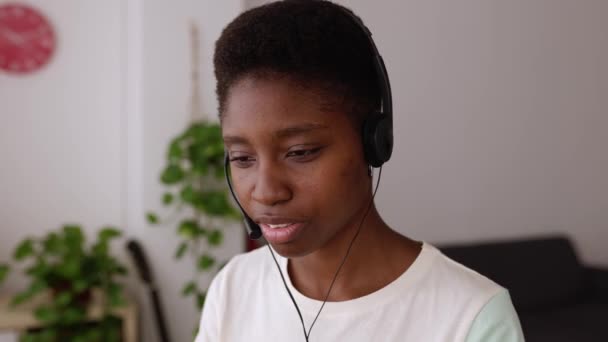 年轻的非洲女人带着耳机在总部工作年轻女子在笔记本电脑上使用视频聊天 呼叫中心代理商与客户交谈的视频镜头 支助服务操作员 — 图库视频影像