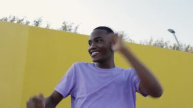 Kulaklıklı, açık havada müzik dinleyen mutlu, Afro-Amerikan bir adam. Milenyum öğrencisi sarı duvarda tek başına eğleniyor. Gençlik kültürü ve mutluluk kavramı