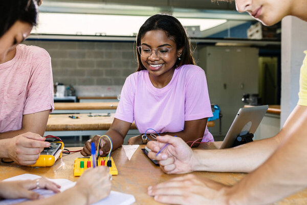 Multiracial students learning electronic at technology lesson - Group of teenager people building and programming electric circuits together in classroom
