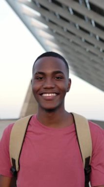 Kameraya gülümserken dışarı çıkan kendine güvenen Afro-Amerikan bir adamın dikey portresi. Yüksek kalite 4k görüntü