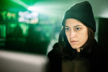 Karanlık odada dizüstü bilgisayarda çalışan profesyonel bir kadın hacker bilgisayarına yanlış veri yükleyen ciddi bir kadına odaklanmış.