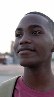 Açık havada dikilen siyah Afrikalı Amerikalı genç adamın dikey portresini kapatın. City Street 'te neşeli Kolombiyalı bir gencin portresi. Yavaş çekim yüksek kaliteli HD görüntüler