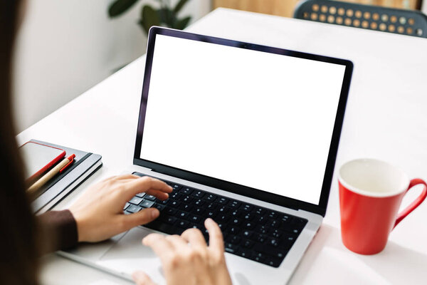 Hispanic latin businesswoman working online on mockup laptop computer with white screen at home office