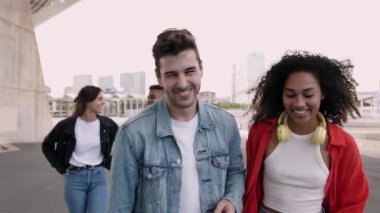 Çok ırklı bir grup genç arkadaş birlikte gülerek dışarıda takılıyor - mutlu çok ırklı insanlar şehir sokaklarında yürürken eğleniyor - arkadaşlık, toplum ve gençlik yaşam tarzı konsepti
