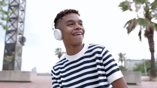 快乐的年轻人 他惊慌失措的年轻男孩 在手机应用程序上 用无线耳机听着他最喜欢的歌曲 慢动作4K镜头 — 图库视频影像