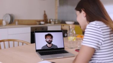 Genç iş kadını, erkek iş arkadaşıyla mutfakta görüntülü konuşma yapıyor. Evde çalışan serbest çalışan bir kadın, yeni bir proje hakkında iş arkadaşıyla sohbet ediyor.