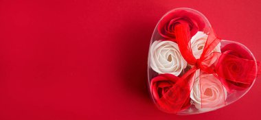 Kırmızı arka planda kalp şeklinde bir kutuda gül şeklinde dekoratif sabun. Sevgililer Günü Konsepti Cilt Bakımı Konsepti Kartpostal Pankartı Üst Görünümü Düz Yatır. Boşluğu kopyala.