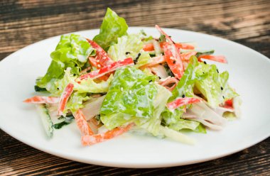 Sebze salatası, marul, yengeç çubuğu, havuç, yoğurt dolu. Taze sebzelerden oluşan parlak bir salata. Yemek arkaplanı. Vejetaryen yemeği. Yan görüş. Yakın plan..
