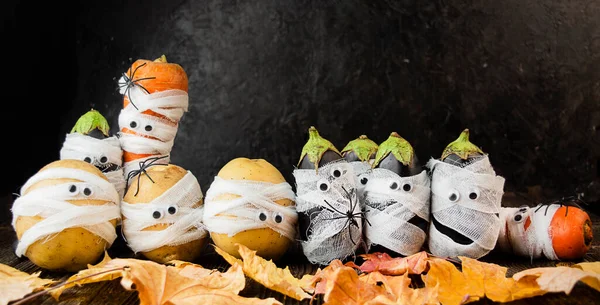 Halloween background. Creepy vegetables with eyes in medical bandages on a dark background. Halloween food. Baner. Copy of the space.
