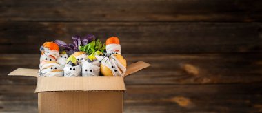 Cadılar Bayramı geçmişi. Ürkütücü sebzeler, ahşap arka plandaki bir kutuda tıbbi bandajlarda gözleri var. Yemek teslimatı konsepti. Taze sebzelerle dolu bir kutu. Cadılar Bayramı yemeği. Baner. Boşluğu kopyala.