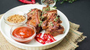 Beyaz bir tabakta pişmiş pirzola. Baharatlı ve otlu ızgara domuz pirzolası. Yemek arkaplanı. Yan görüş. Boşluğu kopyala.