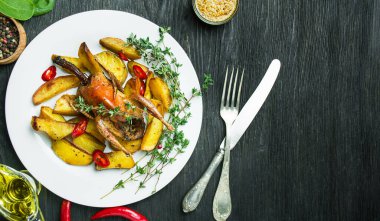 Koyu bir masada patates ve sebzeli fırında bıldırcın. Boşluğu kopyala.