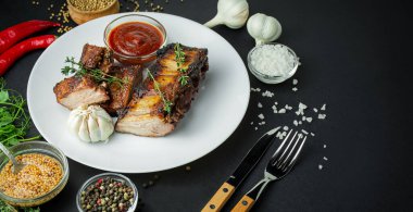 Tabakta pişmiş pirzola. Arka planda baharatlı ve otlu pirzola. Yemek arkaplanı. Yan görüş. Pankart. Boşluğu kopyala.