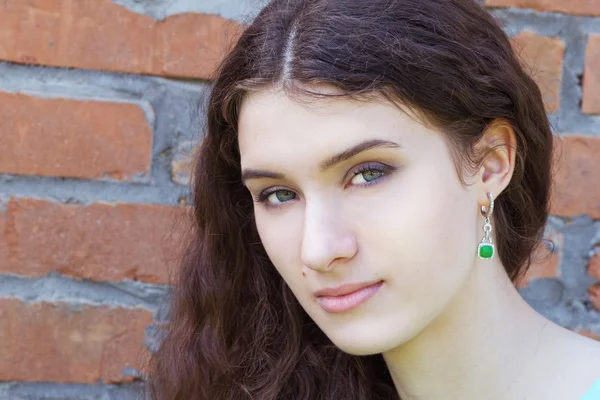 Gros plan portrait d'une belle femme posant contre un mur de briques Photo De Stock