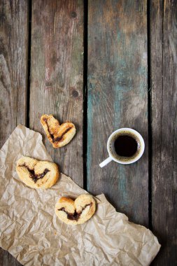 Tahta arka planda bir fincan kahve ve kurabiye.