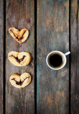 Tahta arka planda bir fincan kahve ve kurabiye.