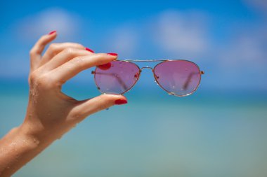 Tropikal plajda güneş gözlüğü tutan kadınlar.