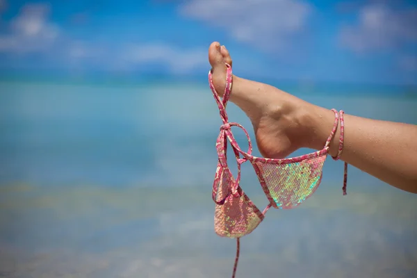 Woman leg hold pink bra isolated on exotic background — Stock Photo, Image