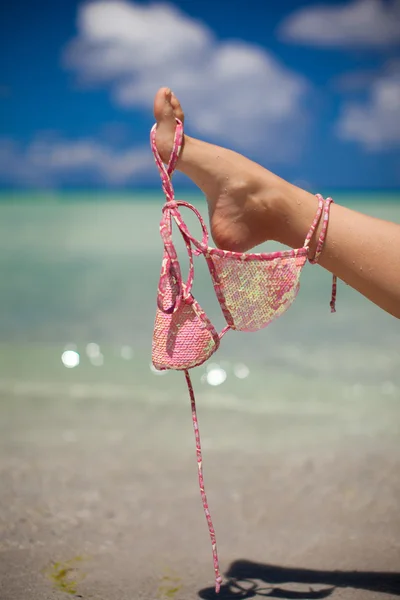 Woman leg hold pink bra isolated on exotic background — Stock Photo, Image