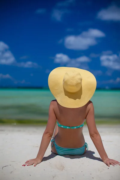 Žena sedí na pláži držel klobouk — Stock fotografie