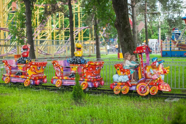 Две маленькие модные милые сестры едут на детском поезде — стоковое фото