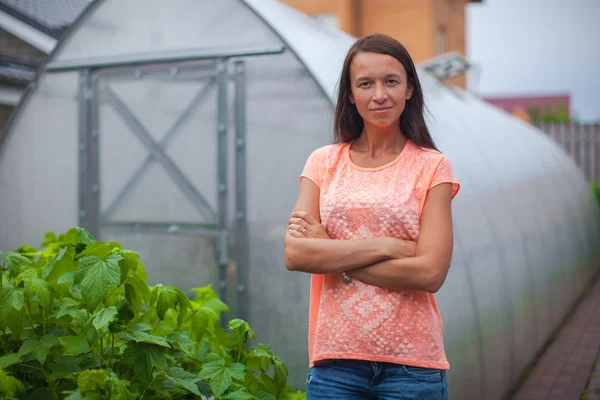Ung kvinna som står nära hennes växthus — Stockfoto