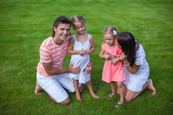 Portrait jeune famille de quatre assis sur l'herbe et amusez-vous — Photo