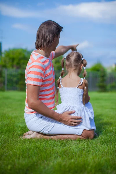 Back view of father with his daughter sitting in the yard outdoors — Stock Photo, Image