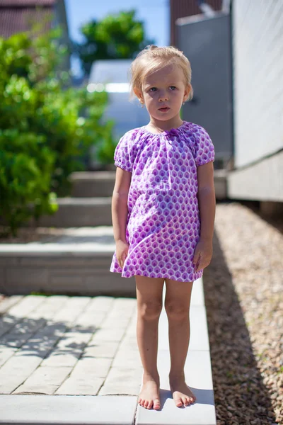 Serious little girl stands in front of her home — Stock Photo, Image