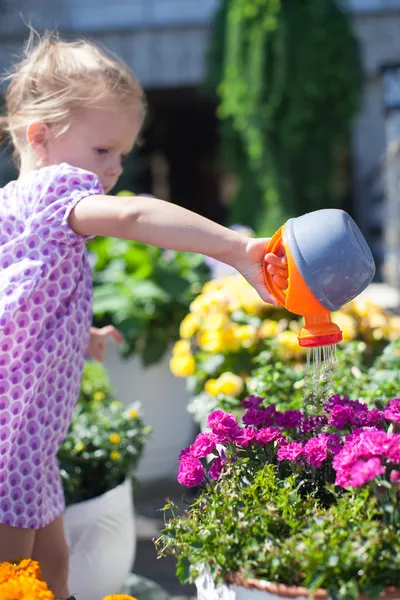 Kleines süßes Mädchen, das mit einer Gießkanne Blumen gießt — Stockfoto