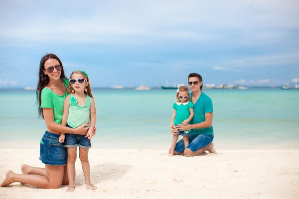 Mom with her older daughter in the foreground and dad with youngest daughter in the background on the beach — Stock Photo, Image