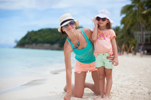 Молодая мать и ее маленькая дочь в шляпах веселятся на пляже — стоковое фото