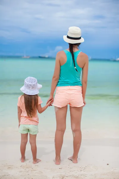 Indietro vista della madre e la sua figlia litlle in cappelli guardando il mare — Foto Stock