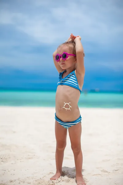 Little girl on her stomach painted a smile by sun cream — Stock Photo, Image