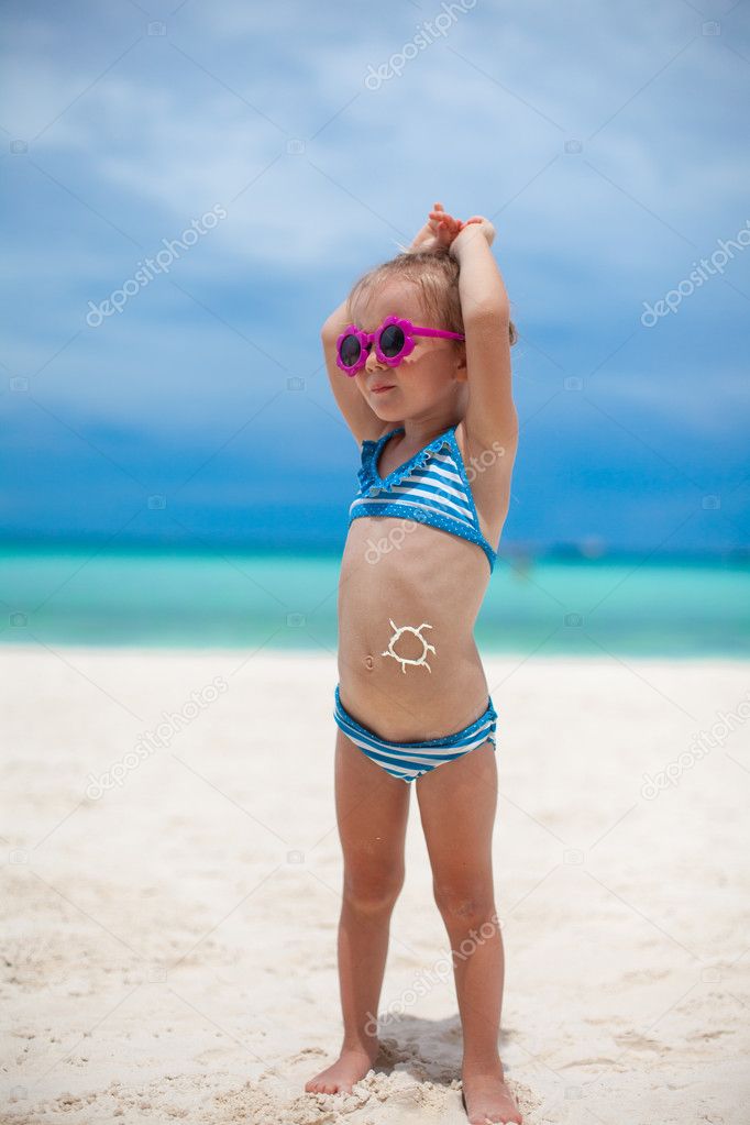 Little girl on her stomach painted a smile by sun cream
