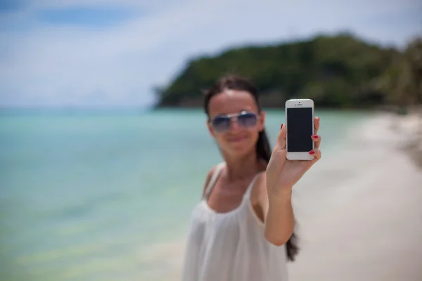 Junge schöne Geschäftsfrau am Strand zeigt Nahaufnahme ihres Telefons — Stockfoto