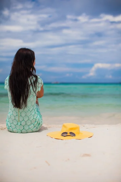 Back view of young fashion woman in dress on the beach and hat near her — Stock Photo, Image