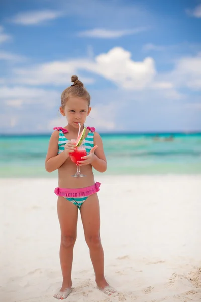 Little girl drinks juice from watermelon on the exotic beach — Stock Photo, Image