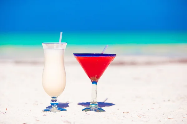Two cocktails: pina colada and strawberry margarita on white sand beach — Stock Photo, Image