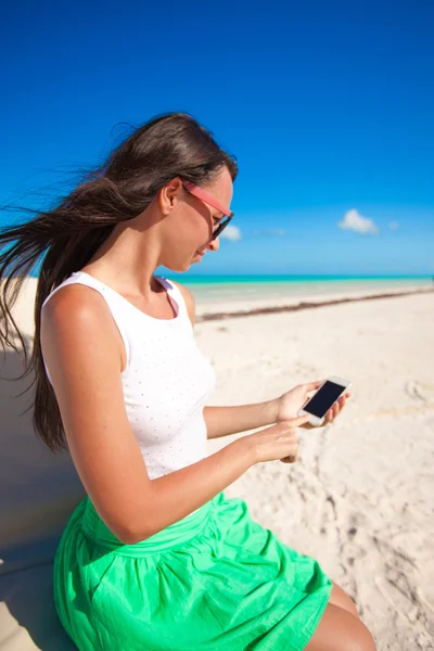 Ung flicka har sin telefon på en exotisk strand — Stockfoto