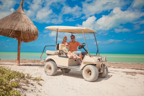 Papá y sus dos hijas conduciendo un carrito de golf en una playa tropical —  Fotos de Stock