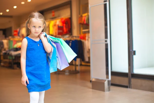 Pequeña chica de la moda sosteniendo bolsas en el centro comercial — Foto de Stock