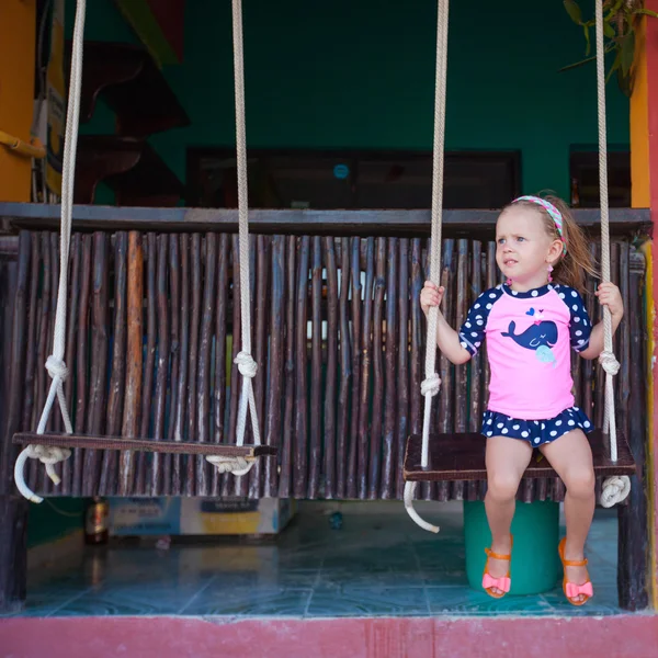 Kleines Mädchen auf einer Schaukel auf der Straße in einem exotischen Land — Stockfoto