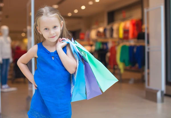 Pequeña chica de moda con paquetes en un gran centro comercial — Foto de Stock