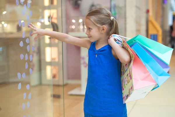 Little girl with packages in a large shopping center — Stock Photo, Image