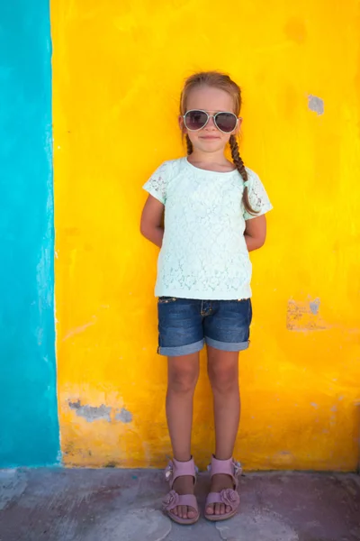 Petite fille mignonne debout près du mur coloré lumineux — Photo