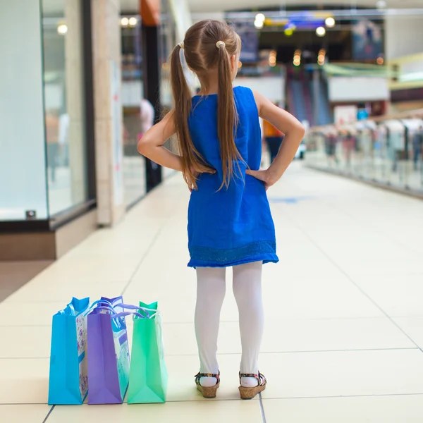Achteraanzicht van mode meisje met pakketten in shopping center — Stockfoto