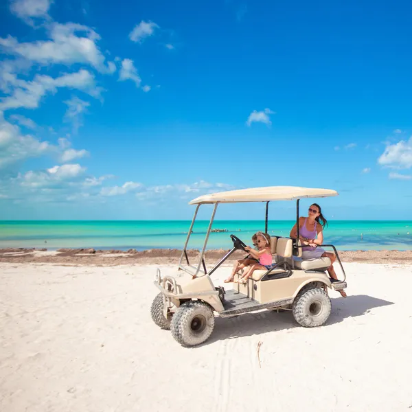 Twee dochters en hun moeder golfkar rijden op tropisch strand — Stockfoto